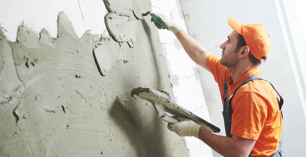 Professionnel du bâtiment appliquant un enduit d'étanchéité sur un mur de sous-sol
