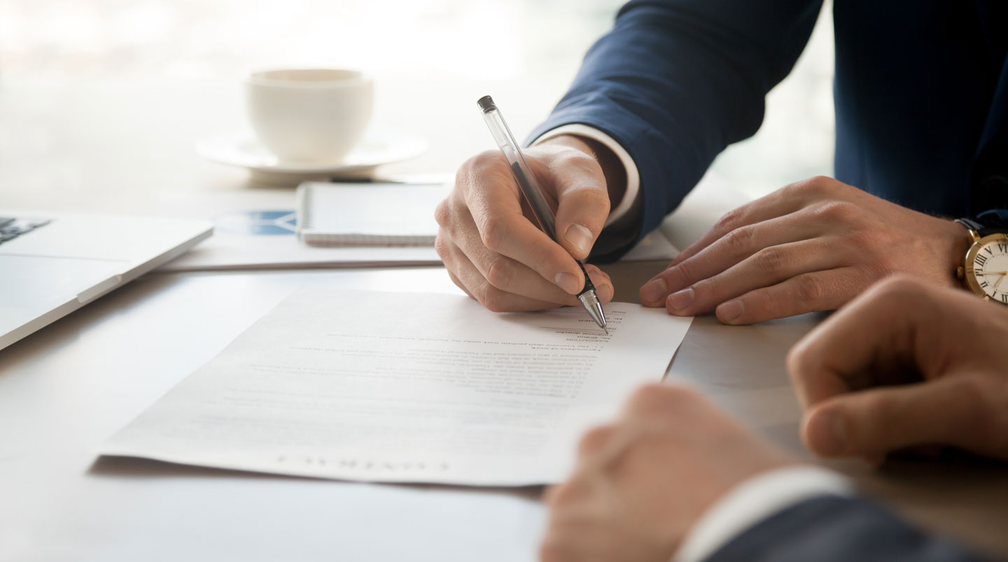 Mains signant un contrat de location de box de stockage sur un bureau sobre